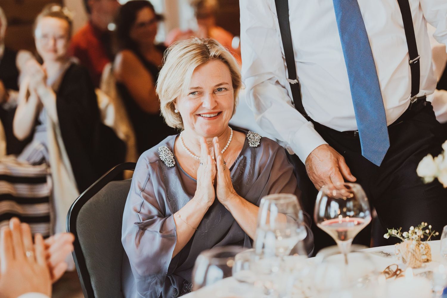 Wedding guests laugh and smile during reception dinner at elegant indoor venue.