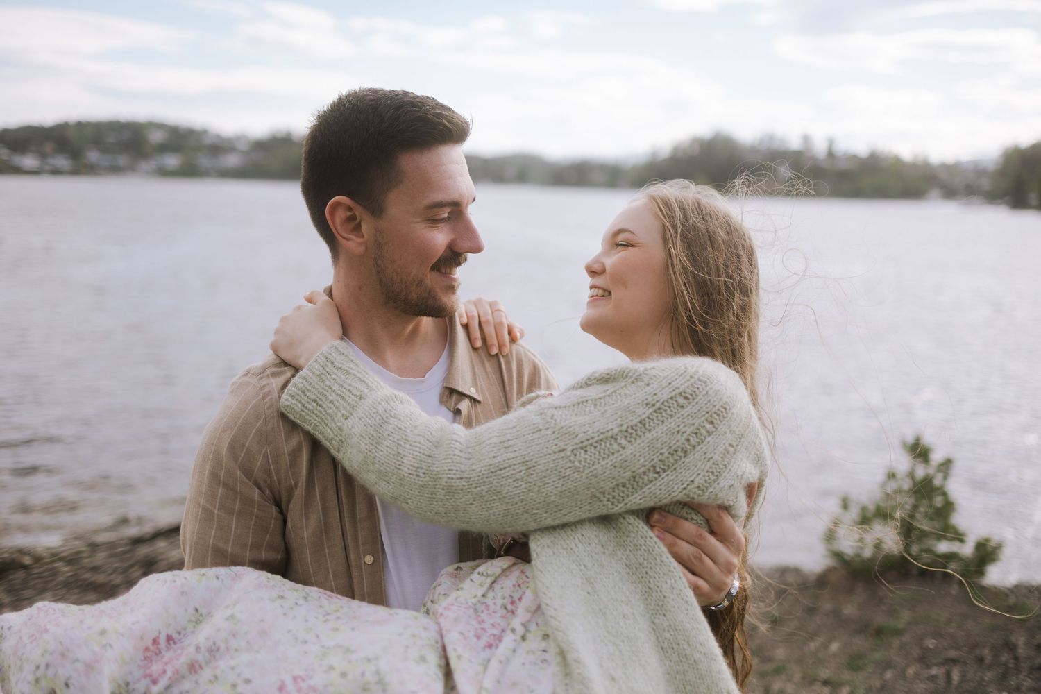 A couple shares romantic moments together along a misty coastline in a series of candid engagement photos.
