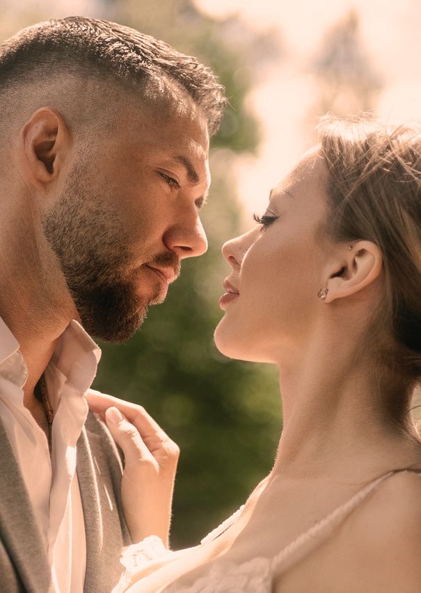 A romantic couple shares an intimate moment at sunset with warm golden lighting and soft focus.