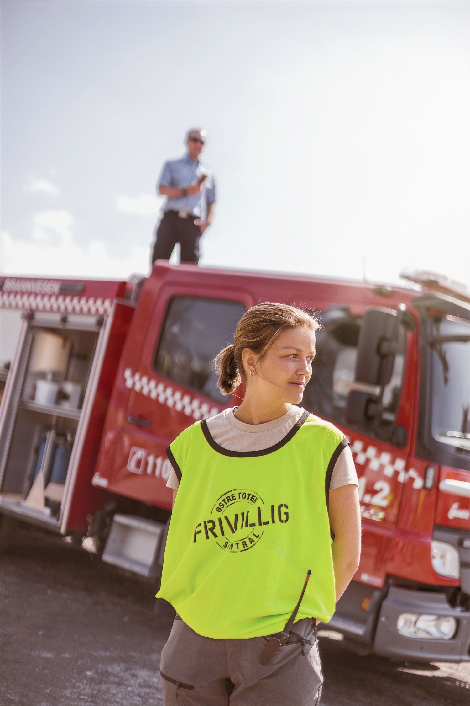 Staff members in bright yellow safety vests stand near red food trucks outdoors.