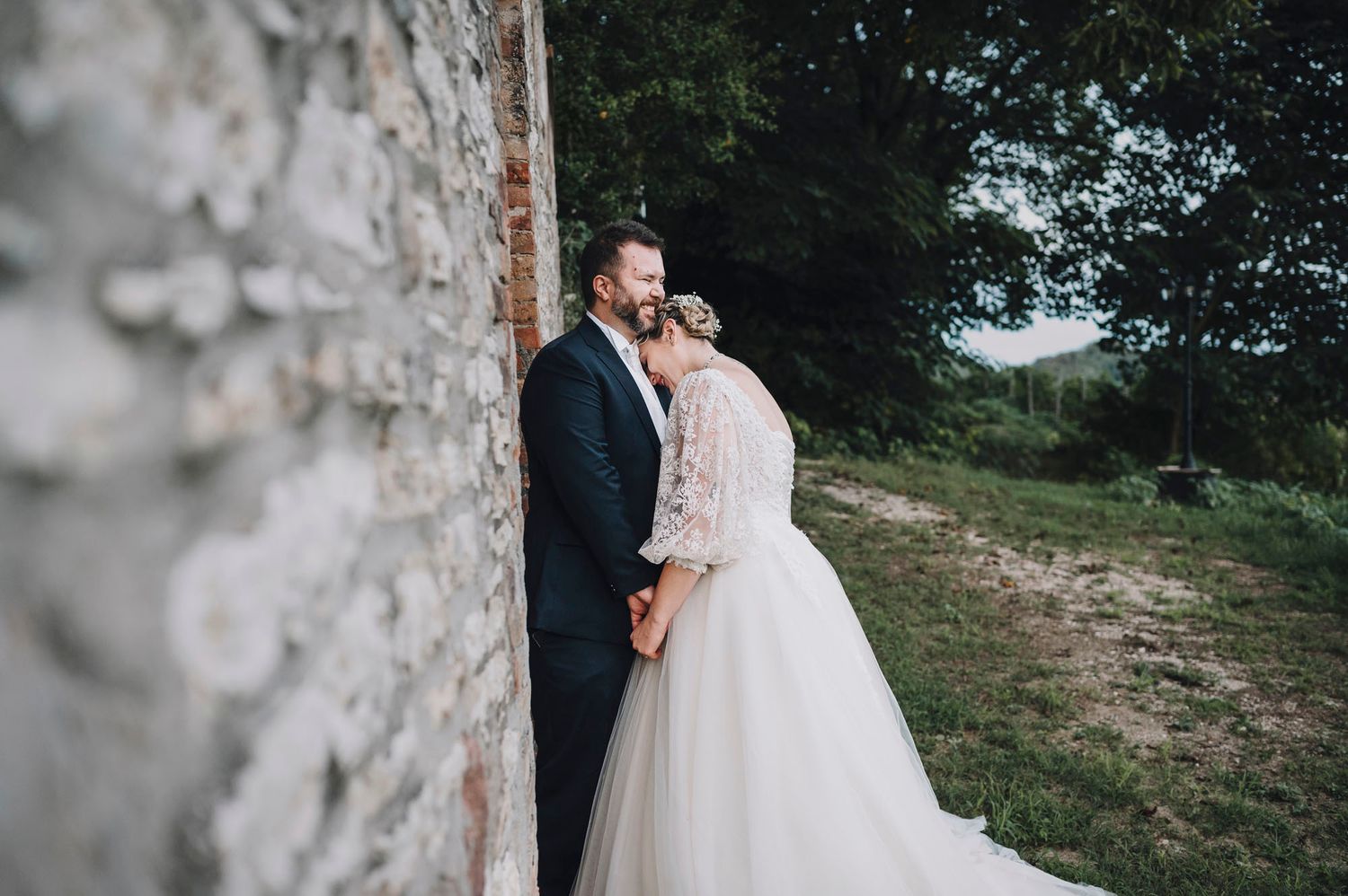 Momento romantico davanti a un muro di pietra in un paesaggio di campagna.