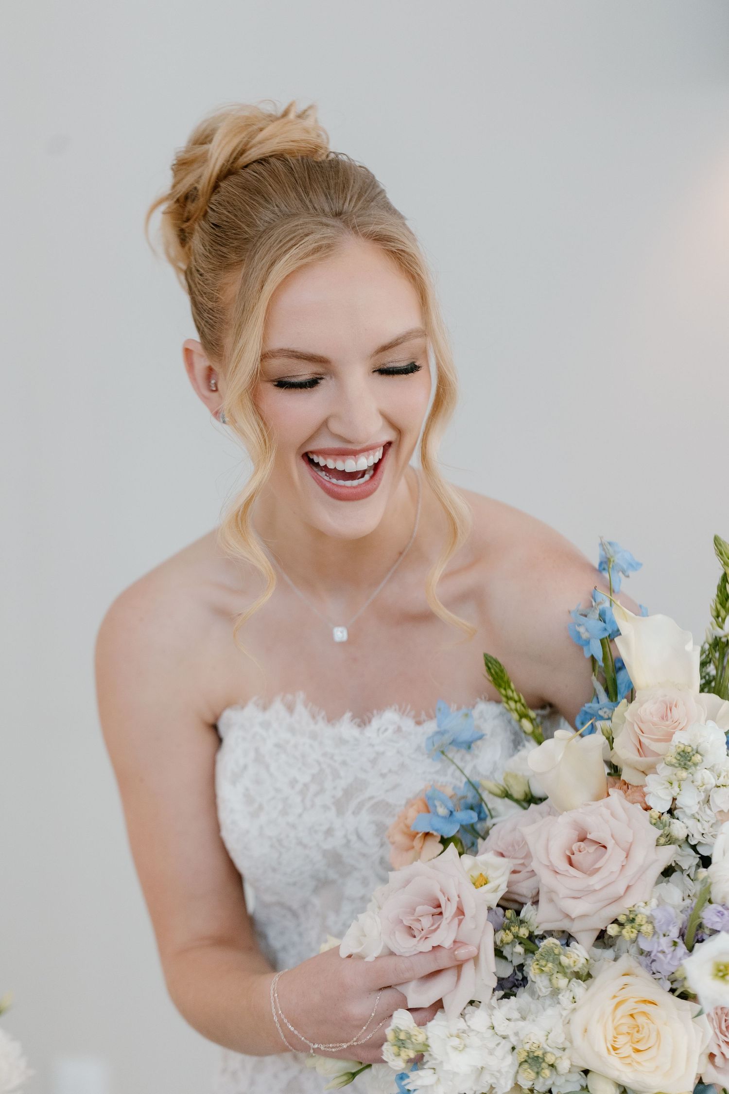 Bride with stunning soft glam makeup by Gaby Makeup Artistry, holding a bouquet of flowers on a sunny day in Oklahoma City.
