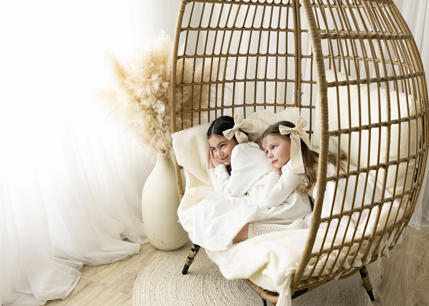 A cozy scene featuring a rattan hanging chair with white cushions and pampas grass decor.