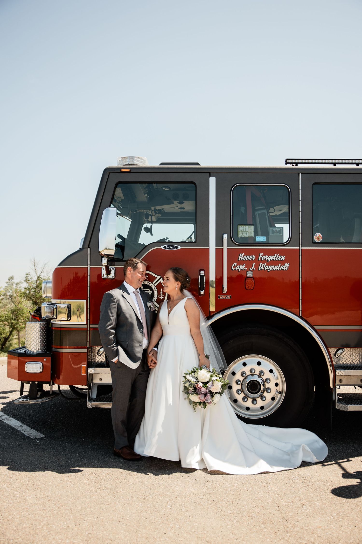 Bride and Groom looking at each other with firetruck behind