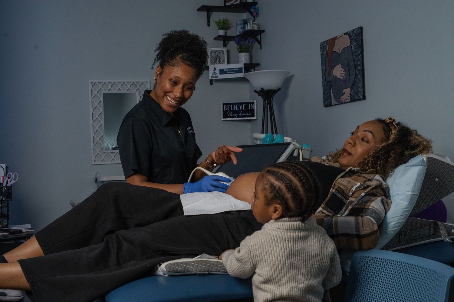A healthcare provider reviews documents with a pregnant woman and child in a cozy medical room.