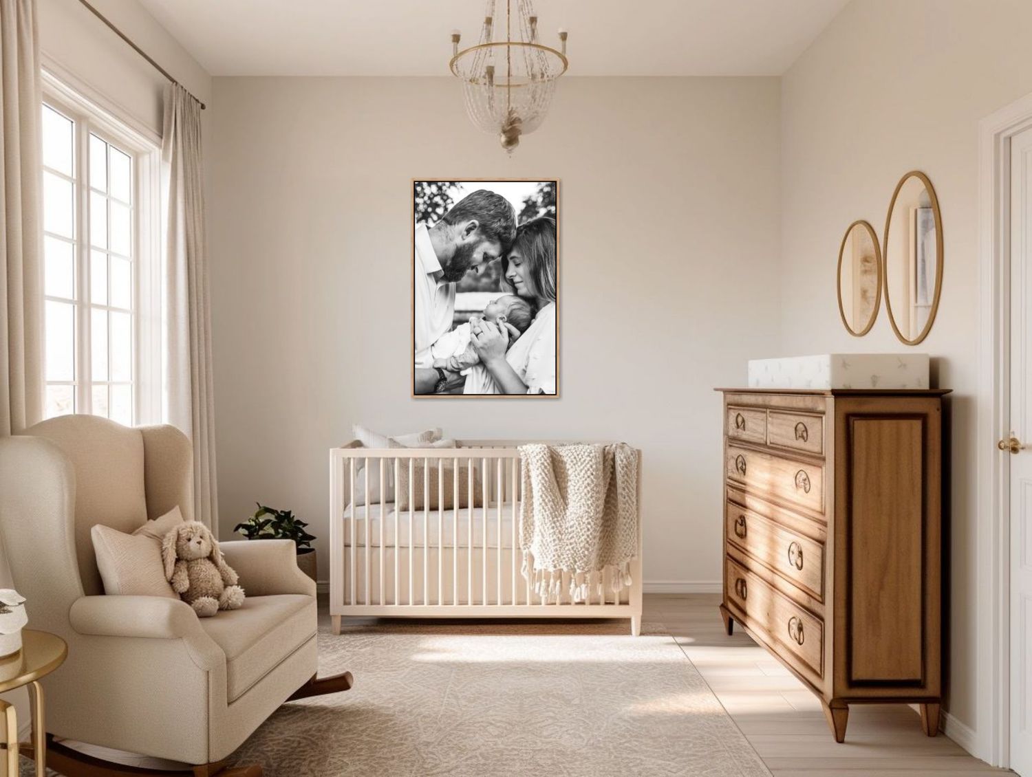 Serene nursery with beige armchair, white crib, wooden dresser, chandelier, and an heirloom family portrait on the wall.