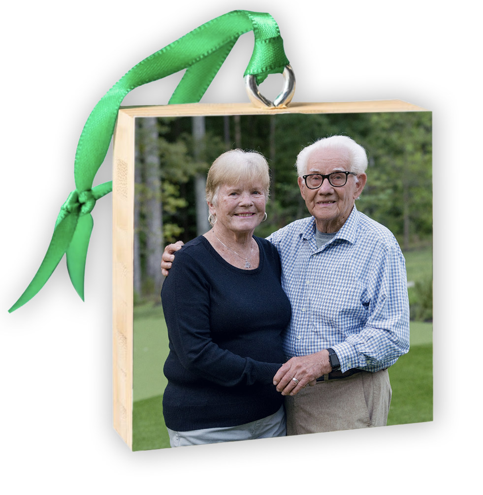 Wooden photo ornament with green ribbon featuring an elderly couple smiling outdoors, perfect for holiday gifting.
