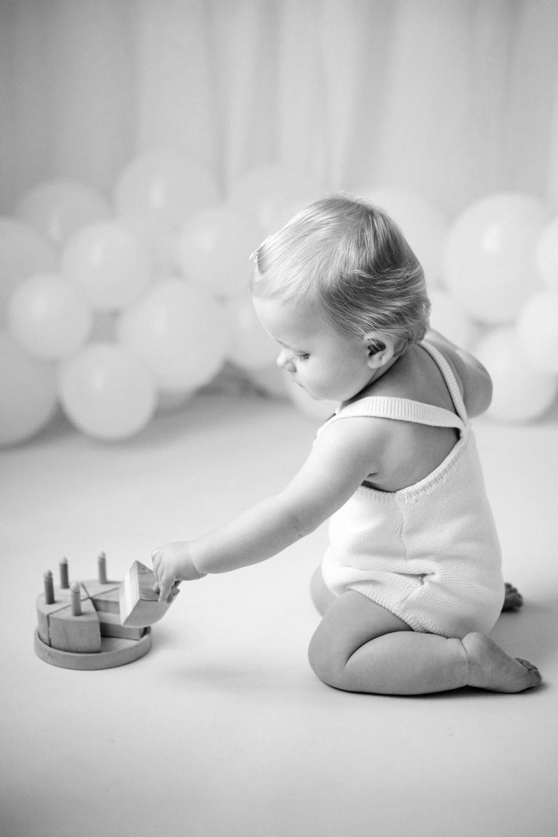 A series of black and white photos showing a baby in white clothing crawling and playing on a light background.