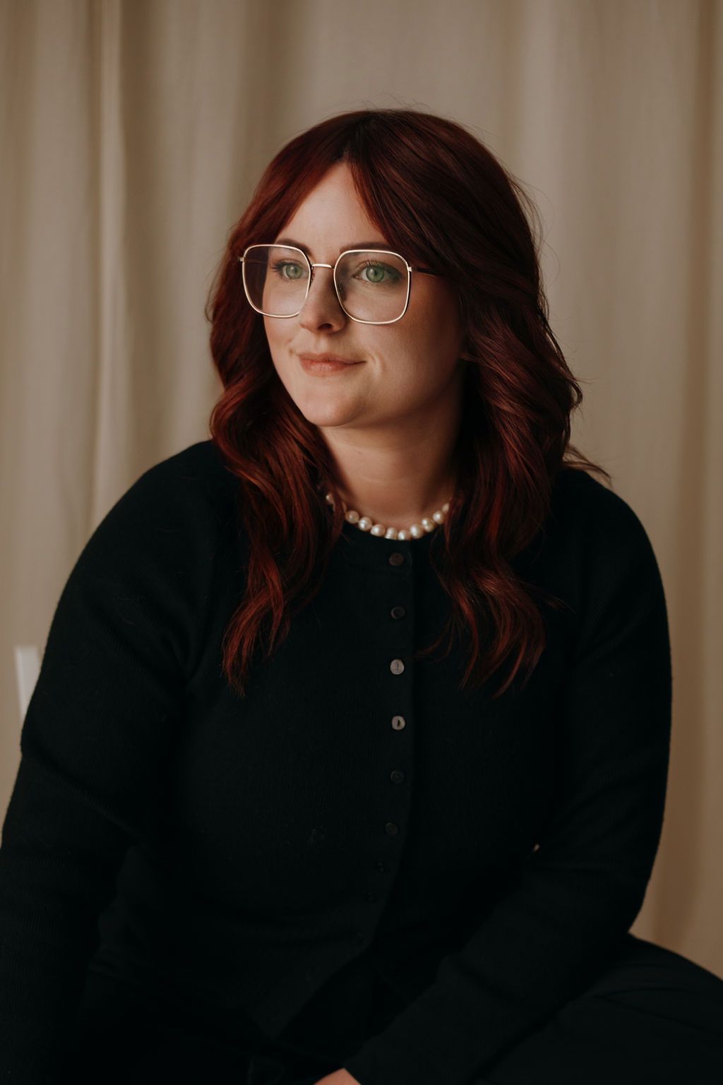 A series of photos showing someone with red hair and glasses wearing a black top against a beige background.