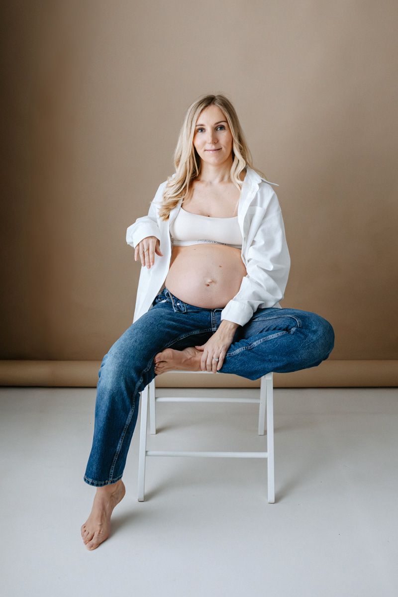 A minimalist portrait series showing a person in jeans and white top seated on a white chair against a neutral wall.
