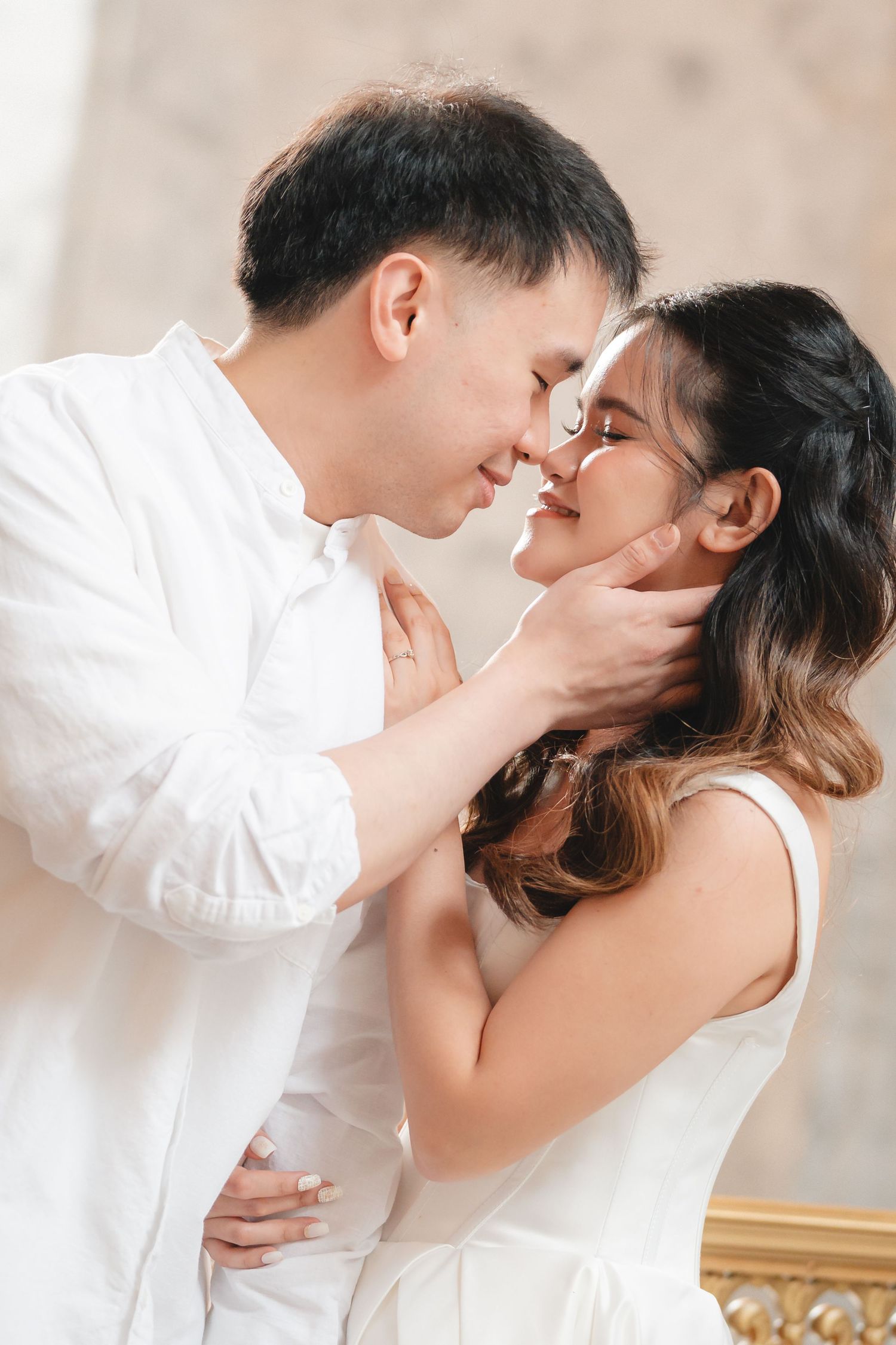 A romantic couple in white outfits share intimate moments in a series of soft, dreamy indoor portrait photographs.