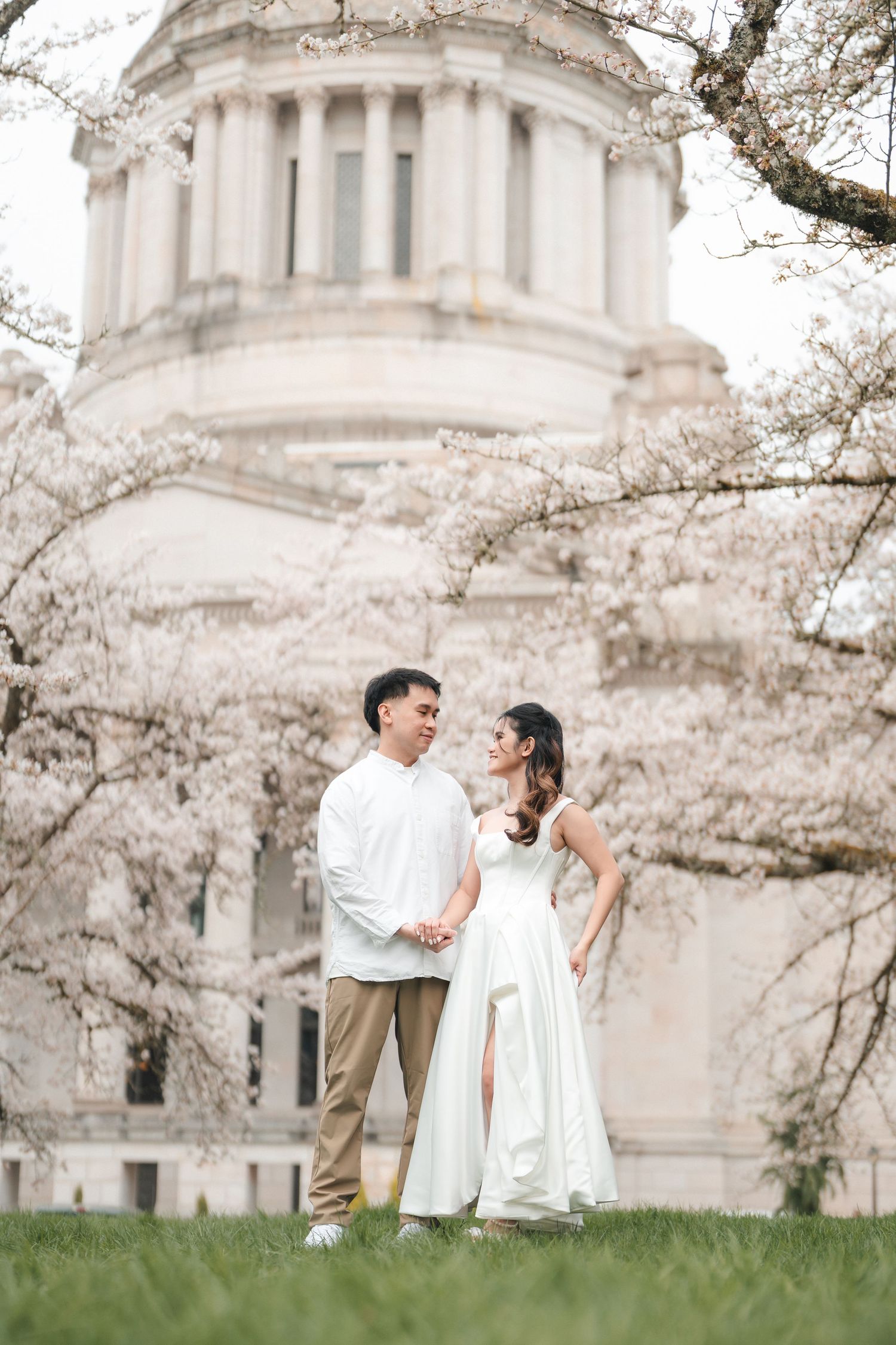 Couple embraces near St Paul's Cathedral in London with blooming cherry blossoms framing the romantic scene.