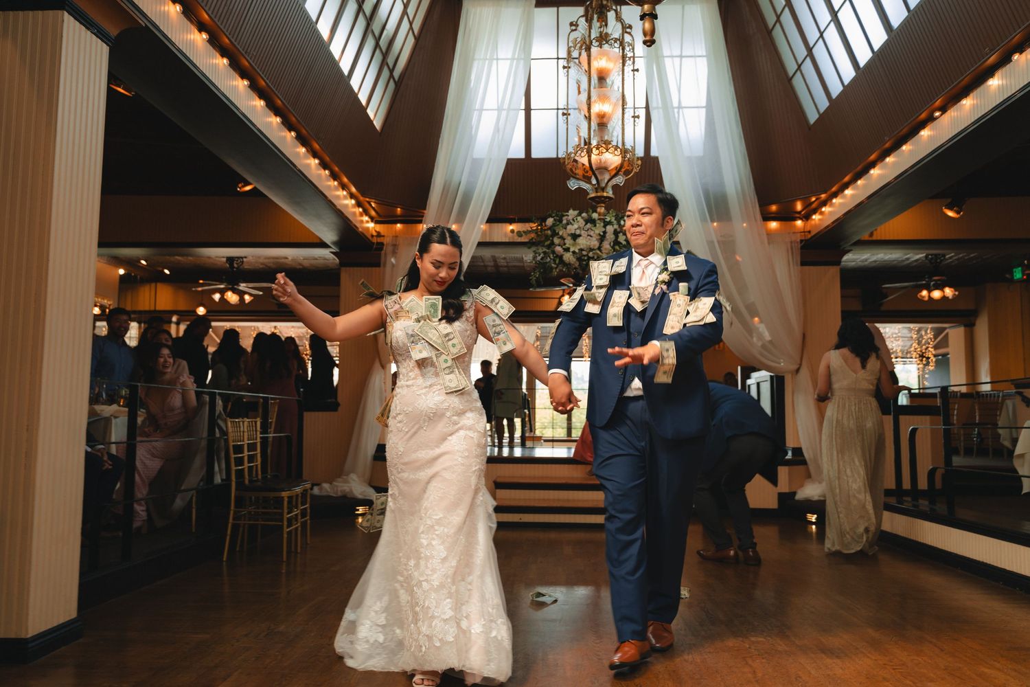 Wedding couple dances together during their first dance in an elegantly lit reception venue.