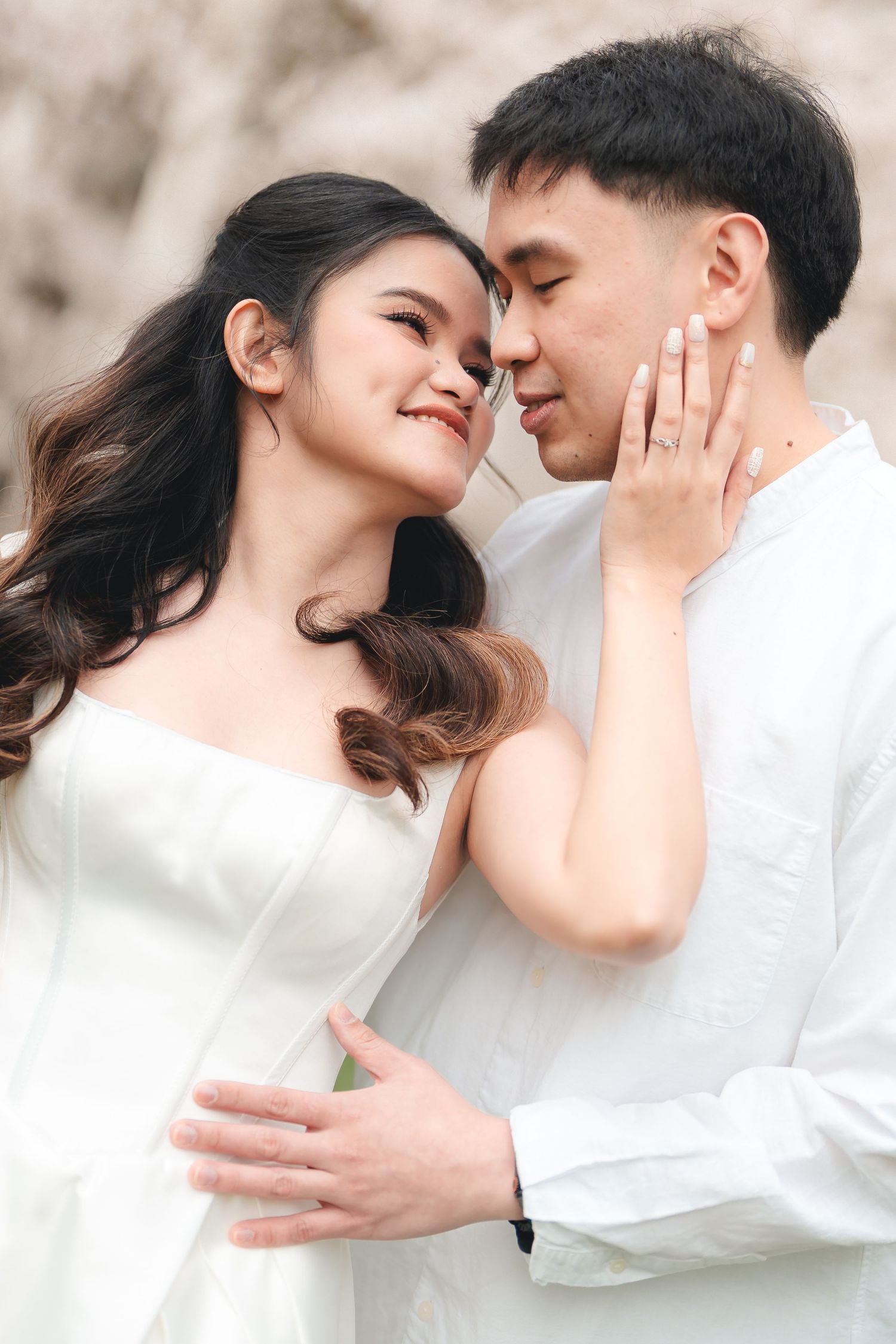 A romantic couple in white outfits share intimate moments in a series of tender embraces against a light background.