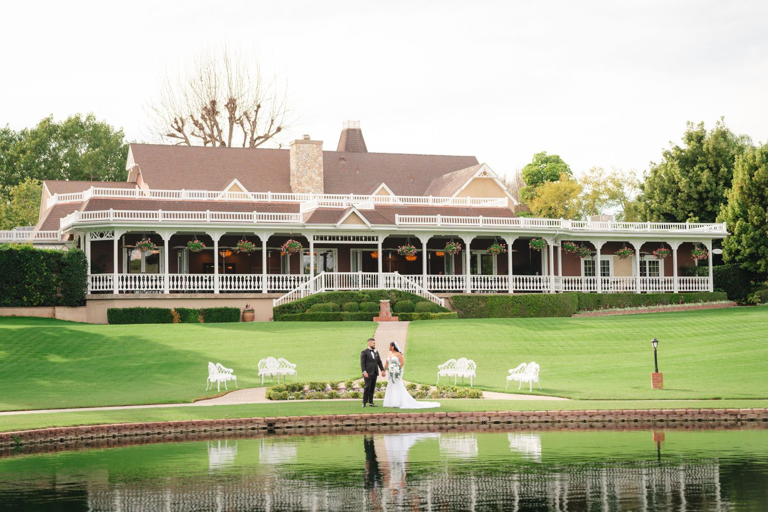 Elegant wedding ceremony setup on a lush golf course with white chairs and a pond view.