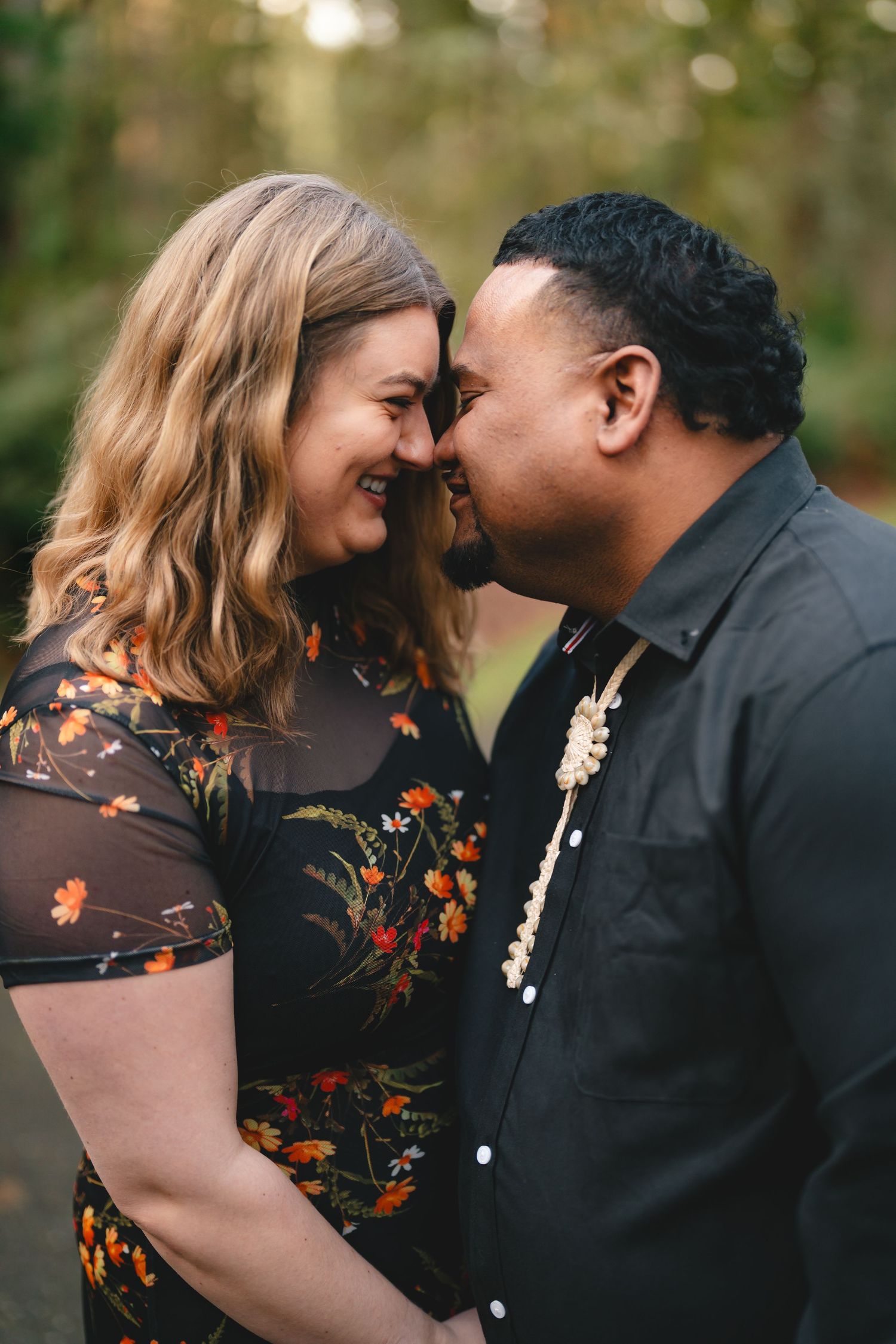 A romantic couple shares tender moments in a series of intimate outdoor photos wearing black and floral attire.