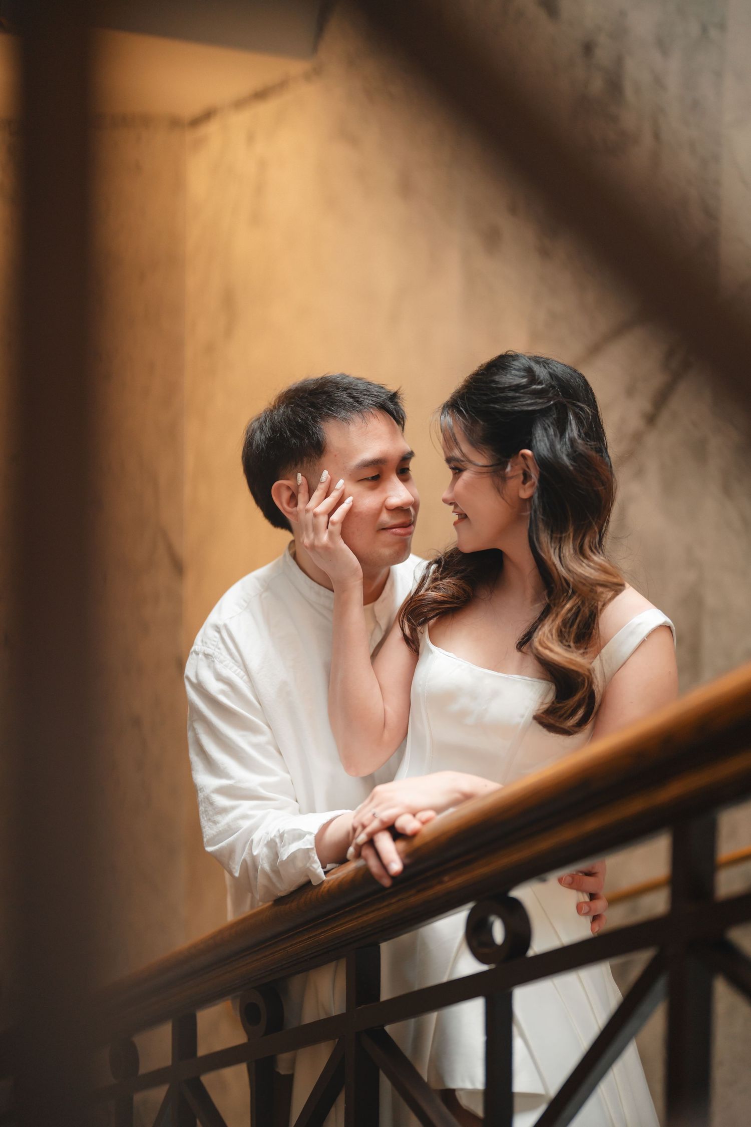 Romantic couple shares intimate moment on vintage staircase in warm lighting.