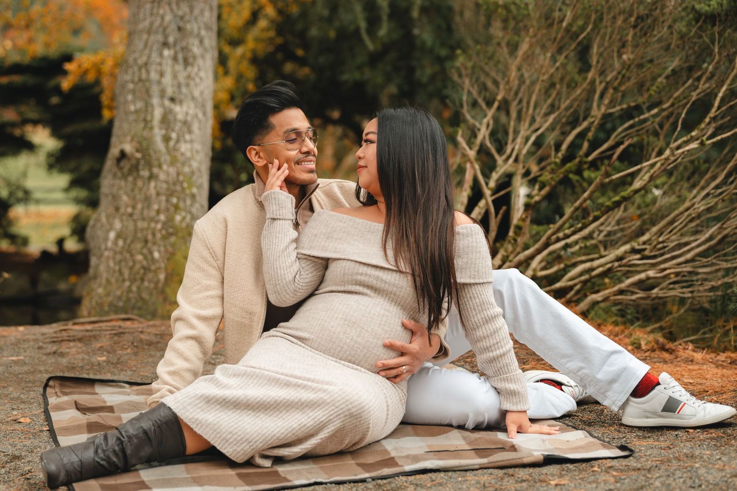 Couple lying on a blanket surrounded by autumn leaves during an intimate outdoor photo session.