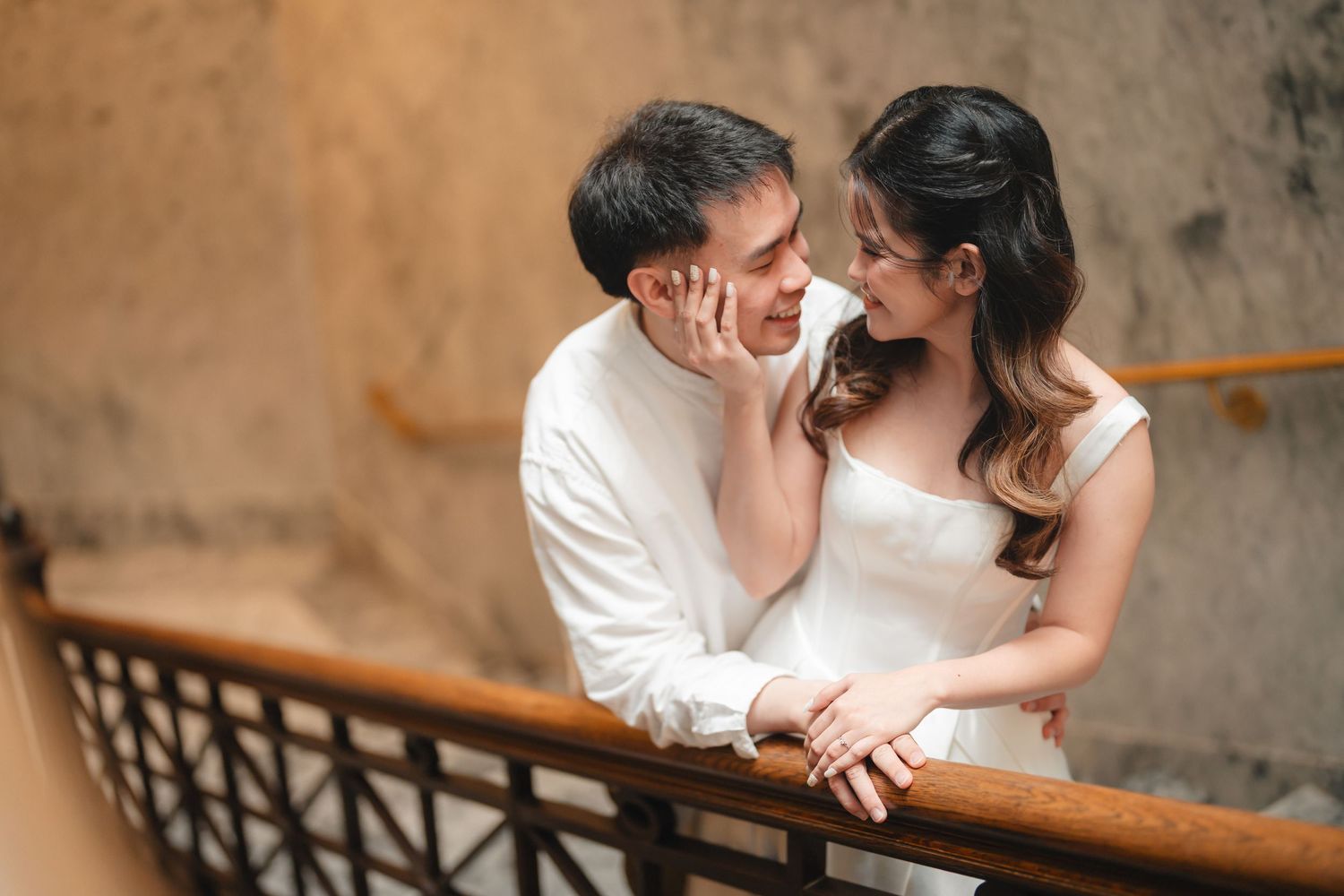 Romantic engagement photo series showing couple embracing against rustic interior background.
