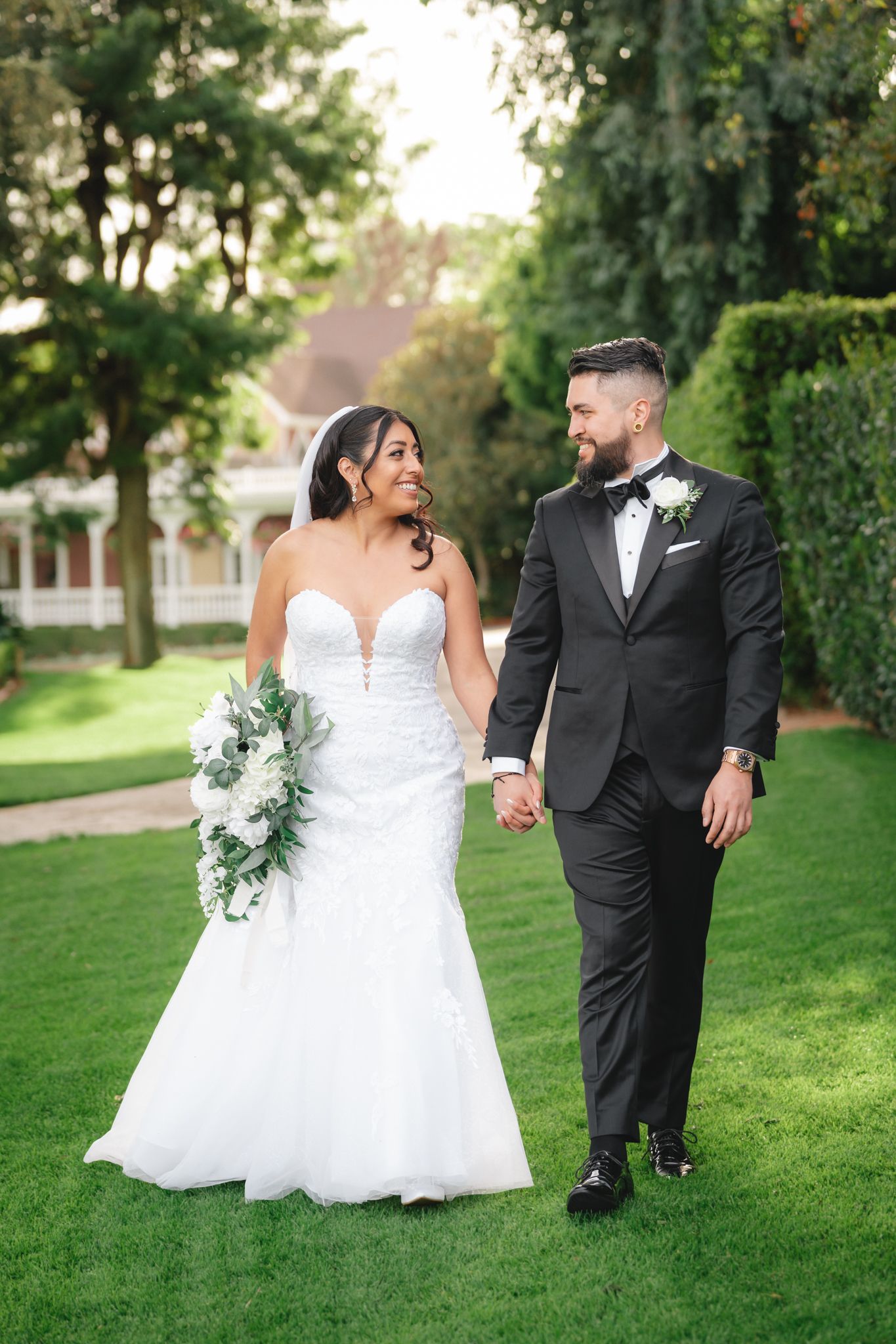 Newlyweds share intimate moments on manicured grounds during their outdoor wedding photoshoot.