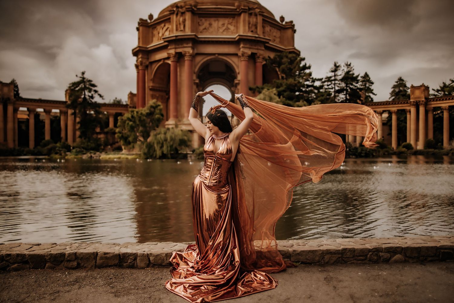 A dramatic photoshoot in flowing red gown at Palace of Fine Arts in San Francisco during sunset with water reflections.