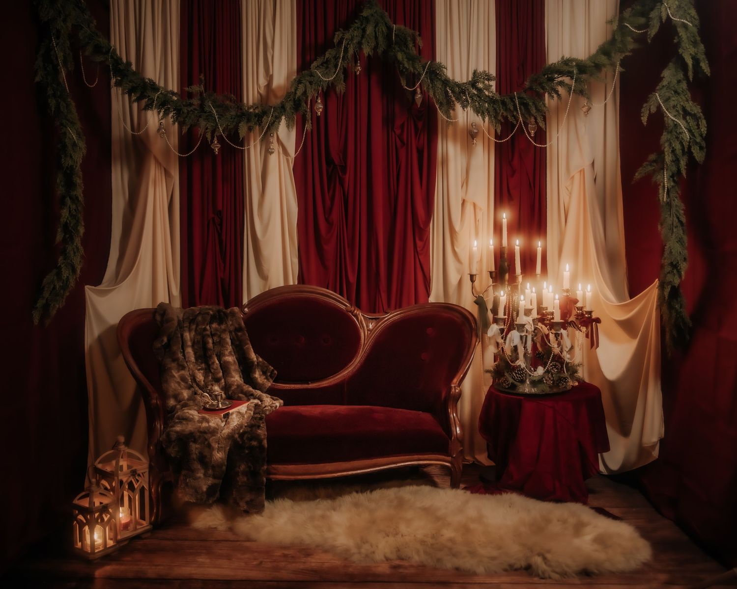 Elegant Christmas vignette with red velvet sofa, candlelit table, garland, and fur throw on a white sheepskin rug.