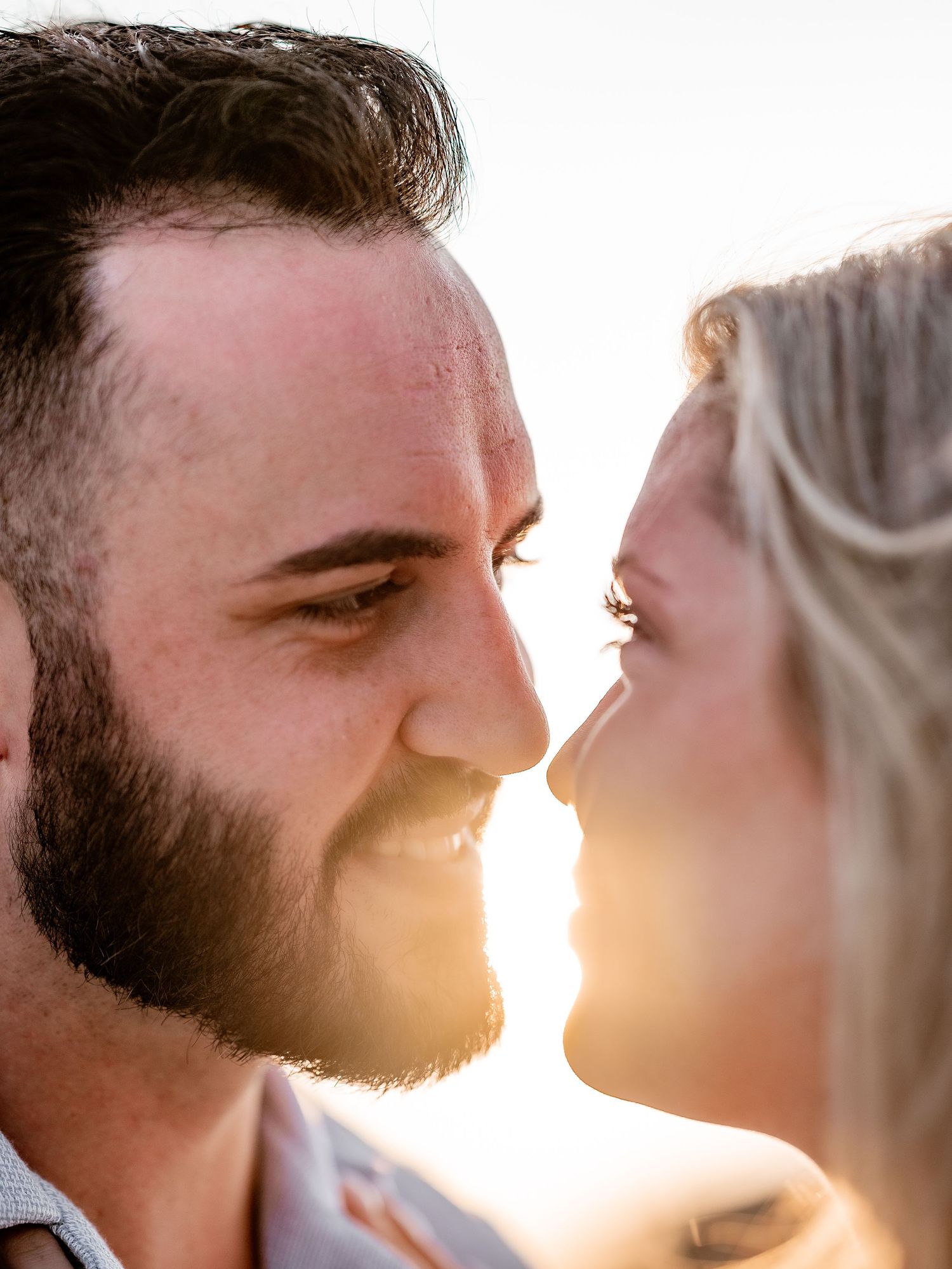 A close-up side profile of two people sharing a tender moment in sunset light.