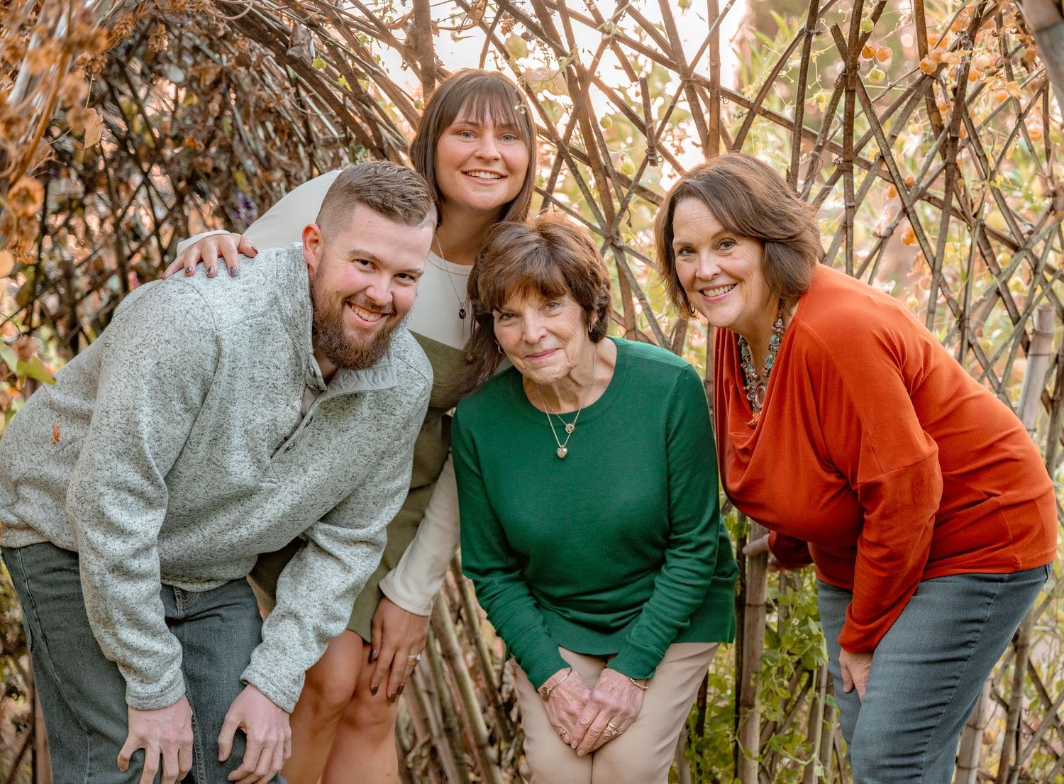 A cheerful group poses together in front of a natural woven branch backdrop during autumn.