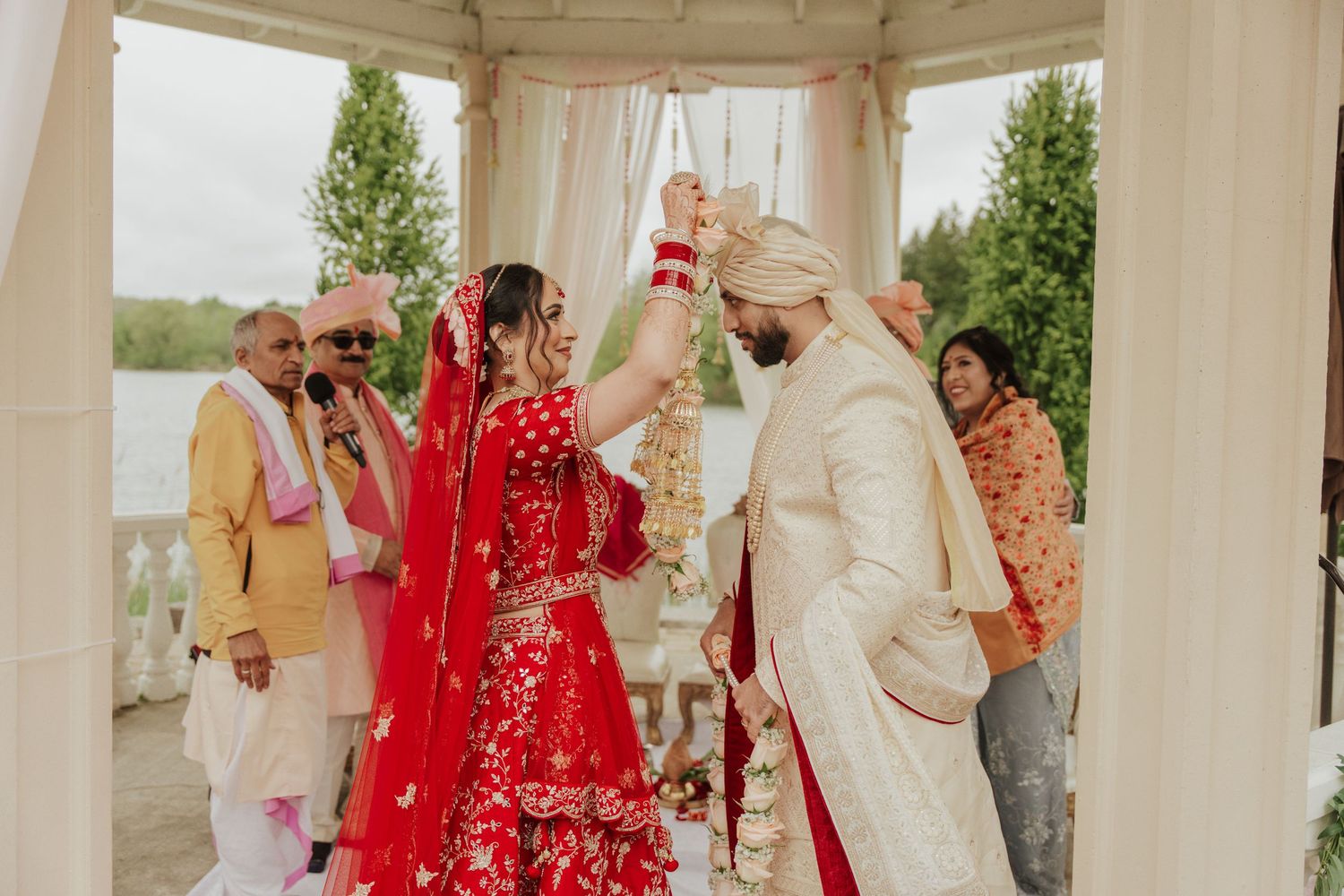 Bride and groom exchanging warmalas (flower garlands) during traditional Hindu wedding ceremony, symbolizing their acceptance and union