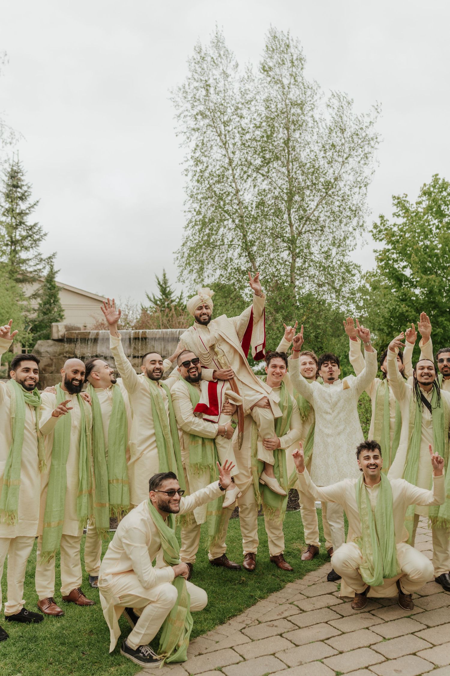 Groom celebrating with groomsmen, enjoying lively moments during wedding festivities in traditional attire in toronto