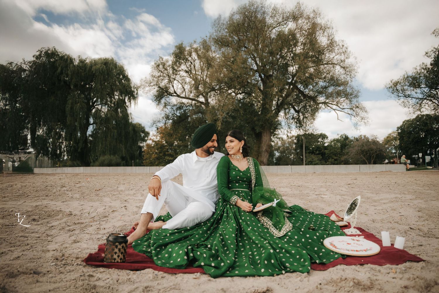 Photoshoot of Punjabi couple sitting close, looking lovingly at each other in vibrant traditional outfits in toronto