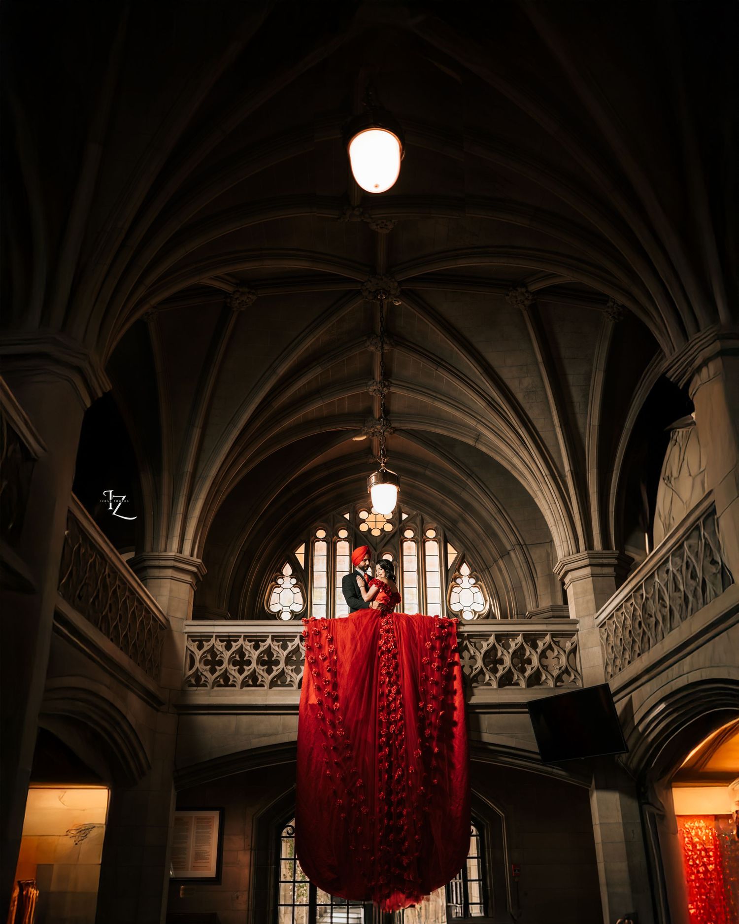 Stylish Punjabi couple at Knox College, bride in flowing red dress set against classic architectural beauty