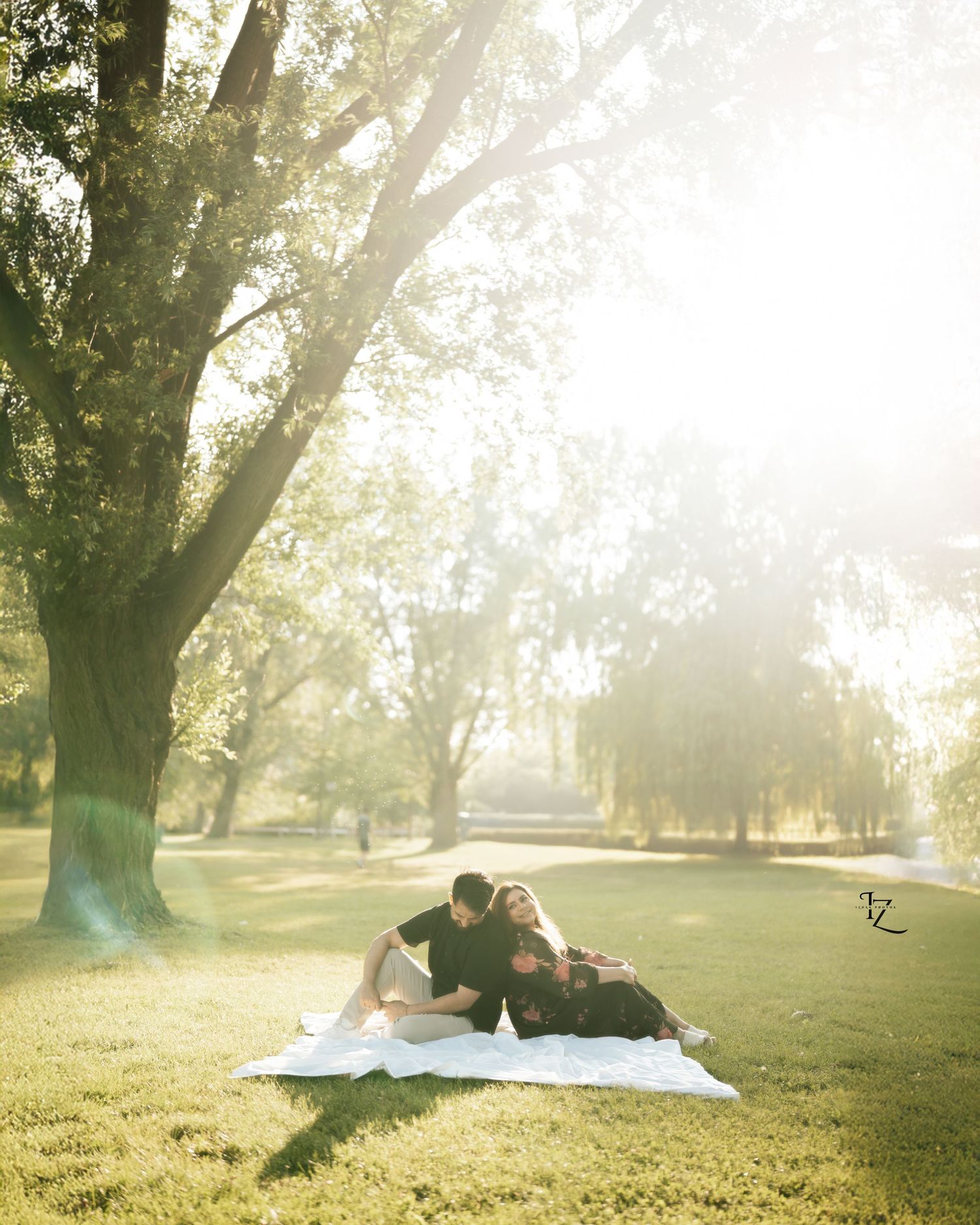 Casual Indian couple sitting and laughing in a park during golden hour, sunlight glowing from behind, capturing natural and joyful moments i