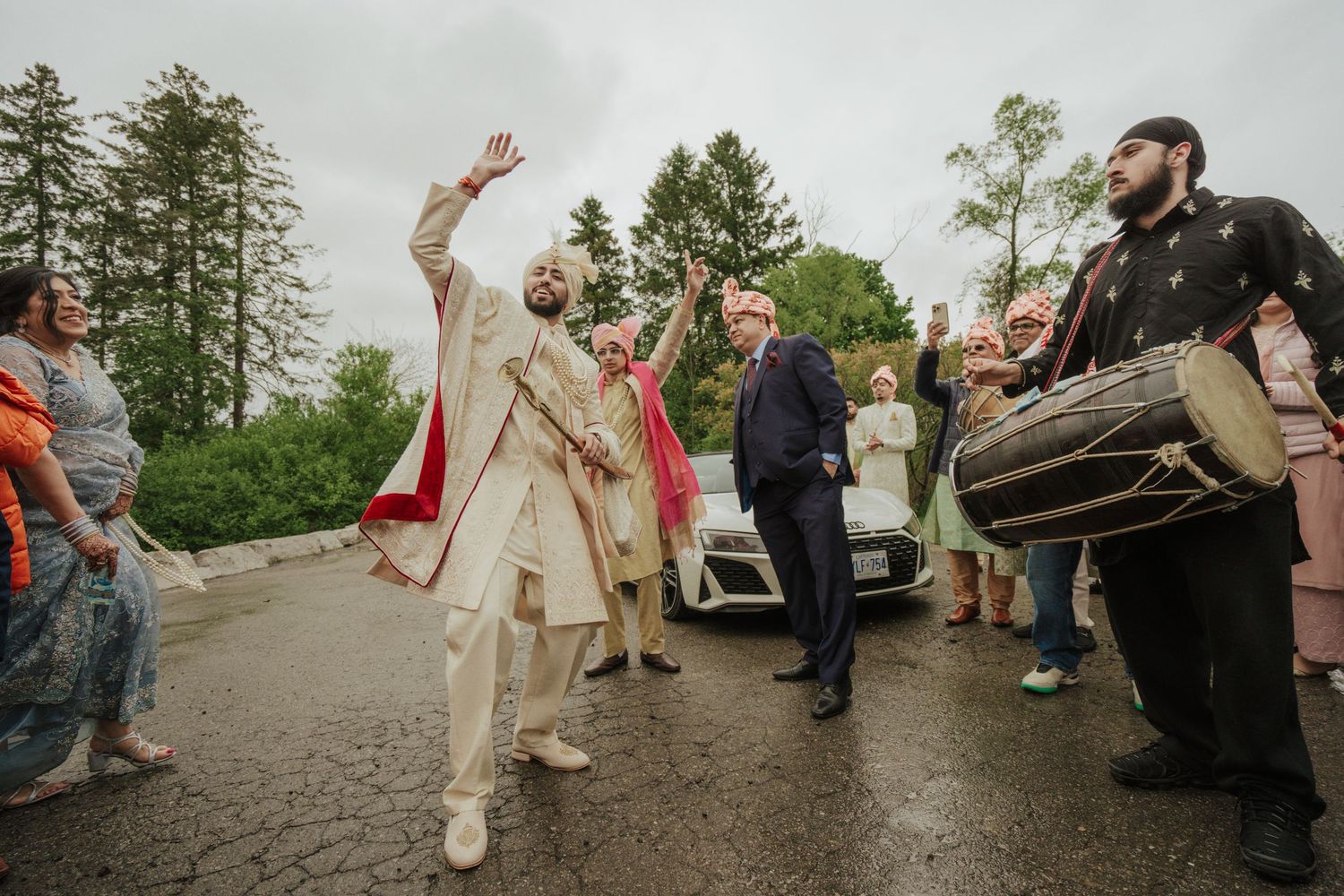 Energetic groom dancing joyfully during baraat procession, surrounded by family and friends in vibrant traditional attire in toronto