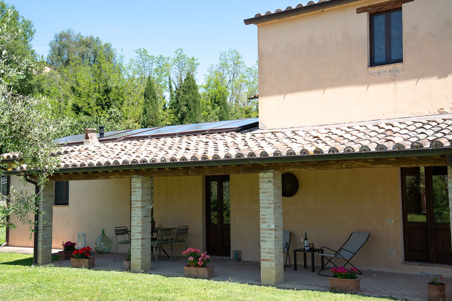 Exterior views of a rustic Italian villa with terracotta roof tiles and cream colored walls in a countryside setting.