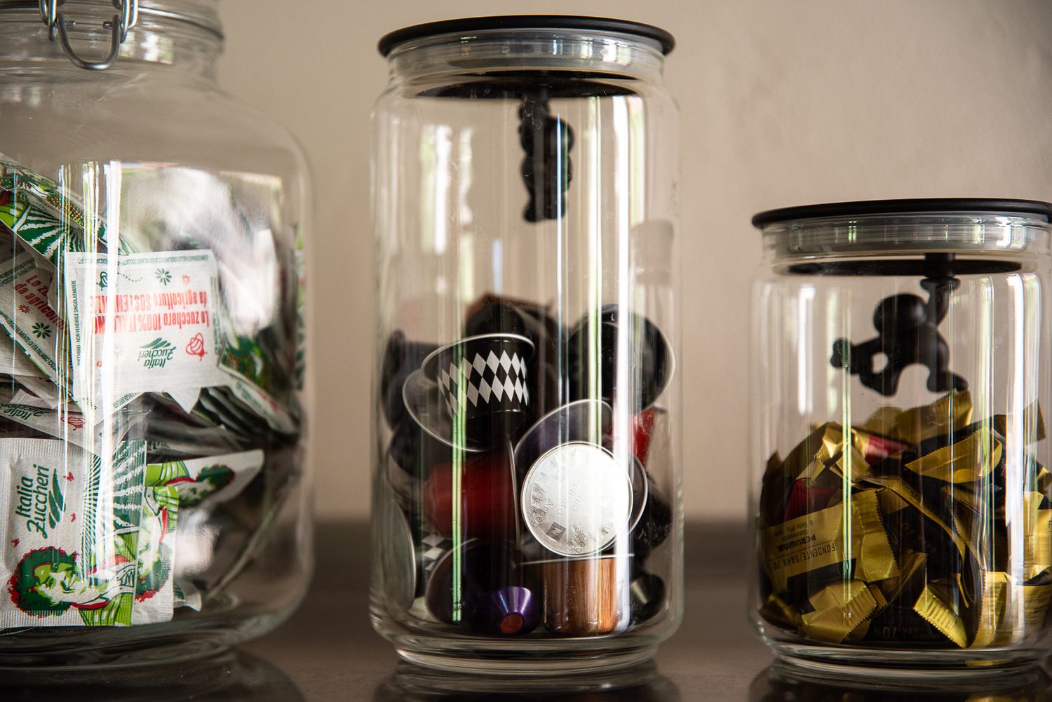 Glass jars containing coffee and sweets lined up on wooden shelves.