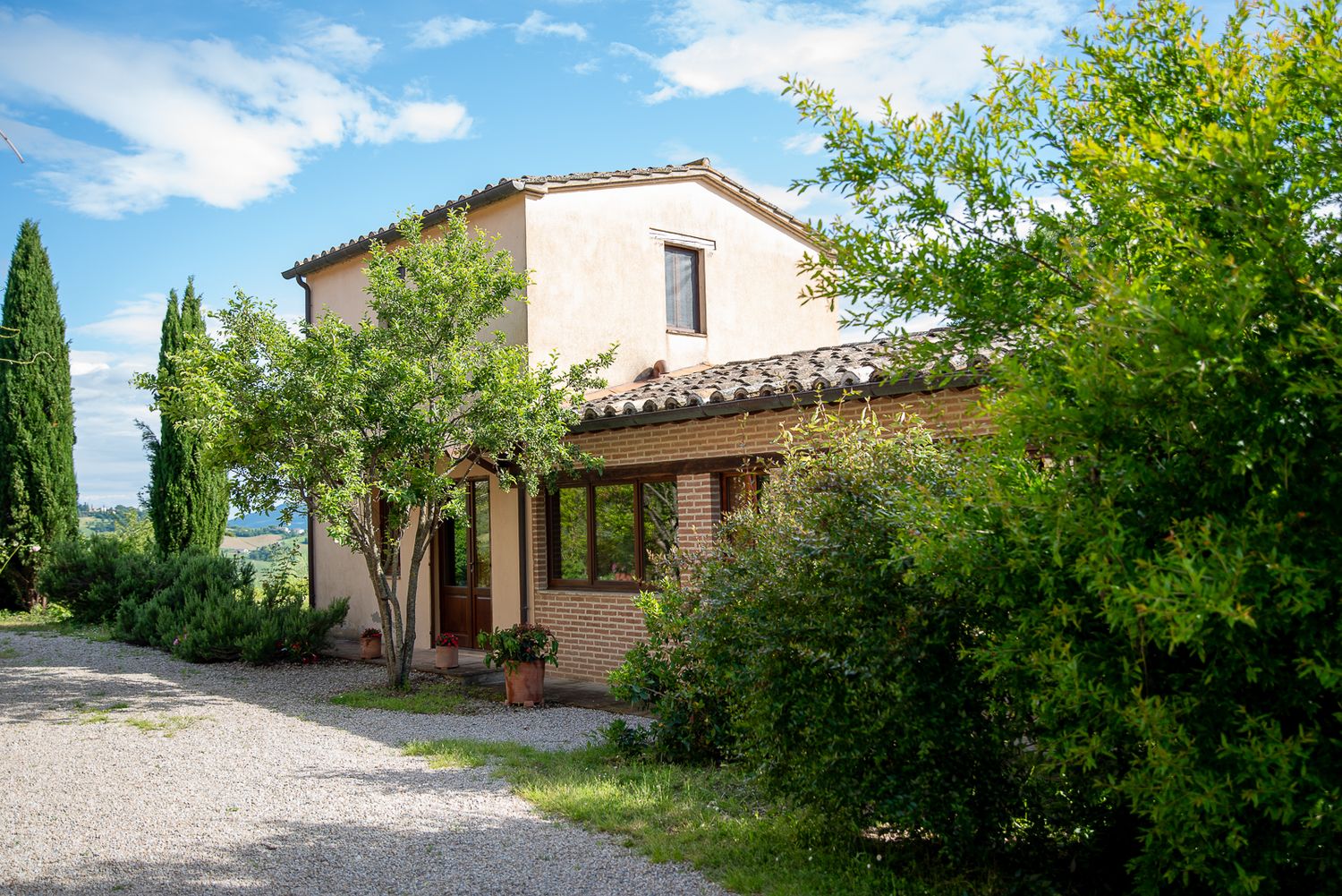 Umbrian villa with cypress trees and landscaped gardens under blue skies.