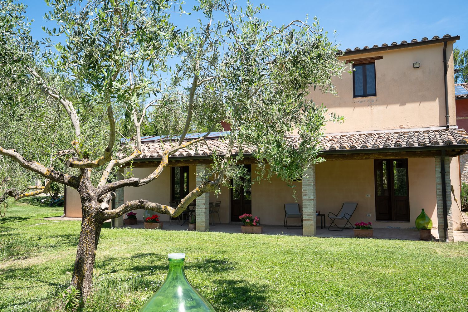 Panoramic view of rustic Italian villa with olive trees and lush gardens in Umbria.