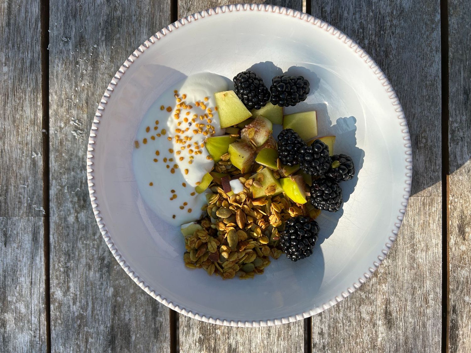 Fresh blackberries and granola served in white bowls against a rustic wooden background.