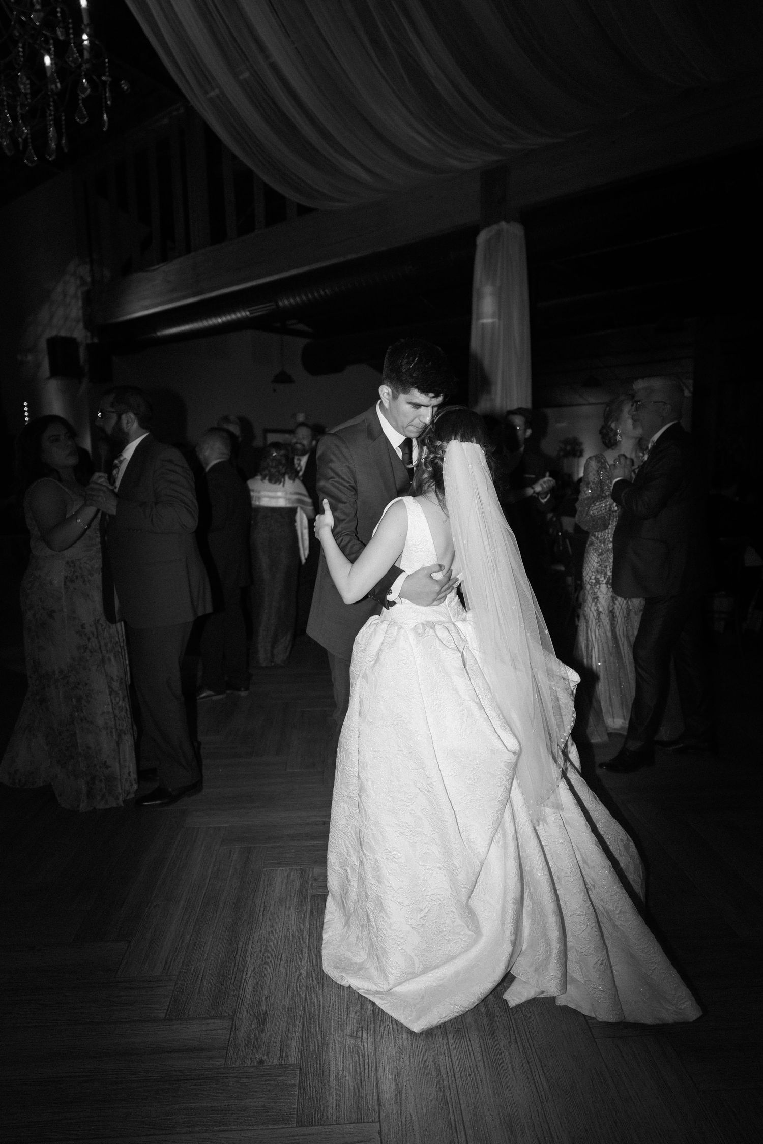 Black and white photo of a wedding dance on a wooden floor.