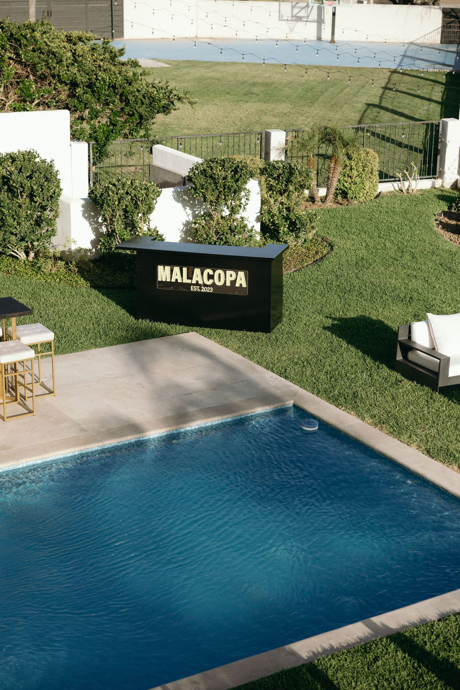 Large blue swimming pool surrounded by manicured lawn at an event venue.