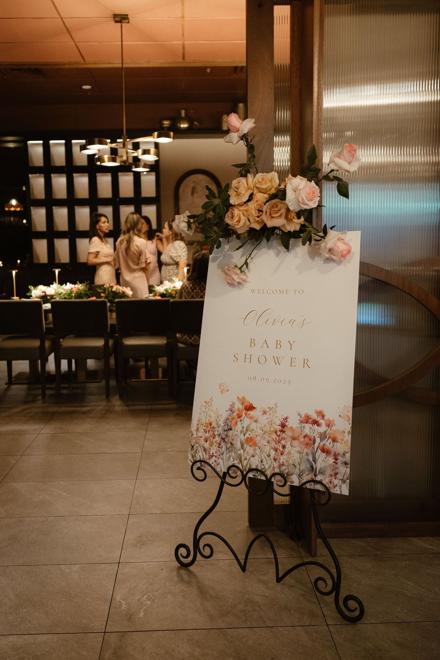 Decorative welcome signs with floral designs displayed on black metal stands.