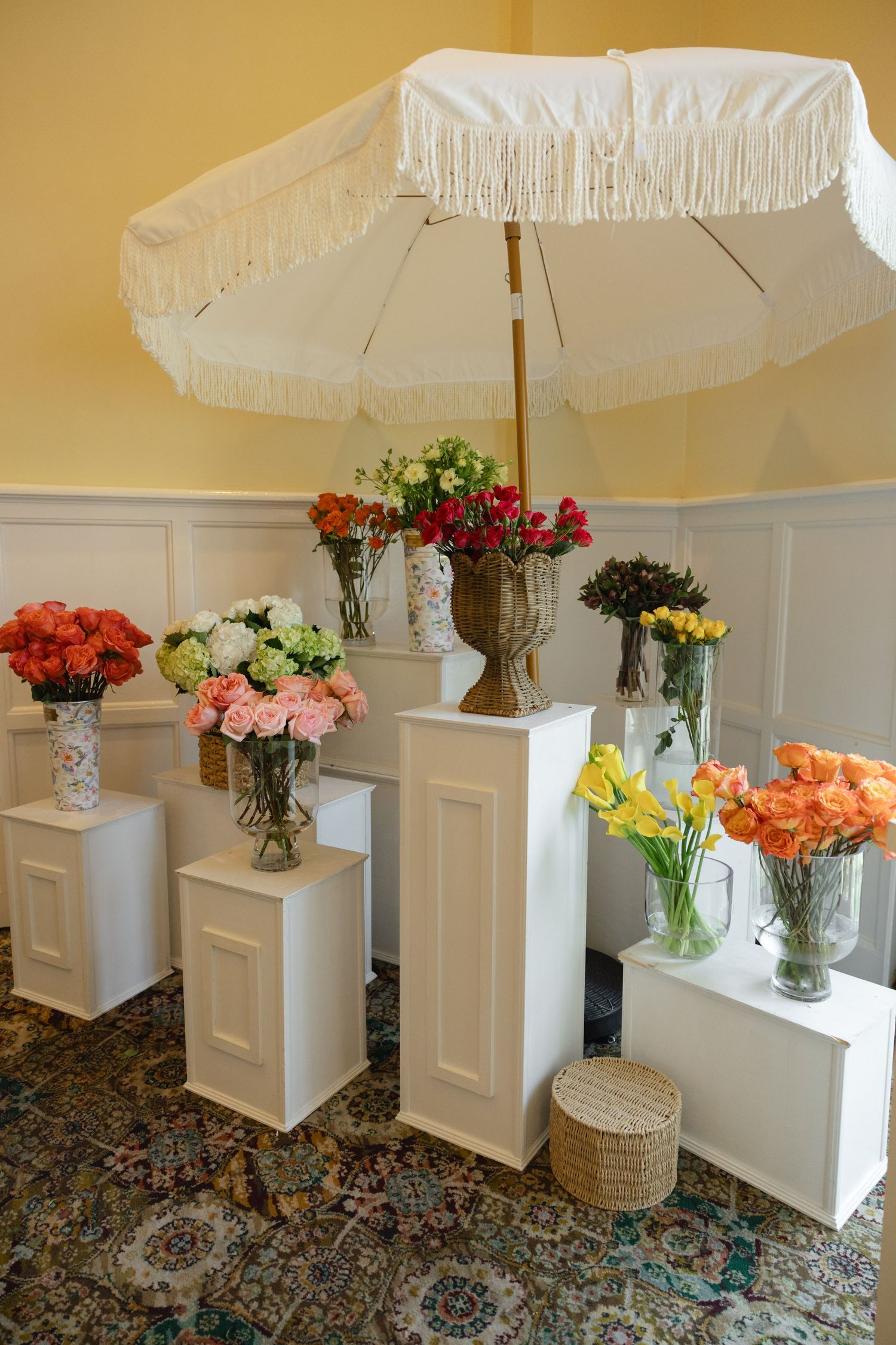 White parasols and pedestals displaying fresh flower arrangements in glass vases.