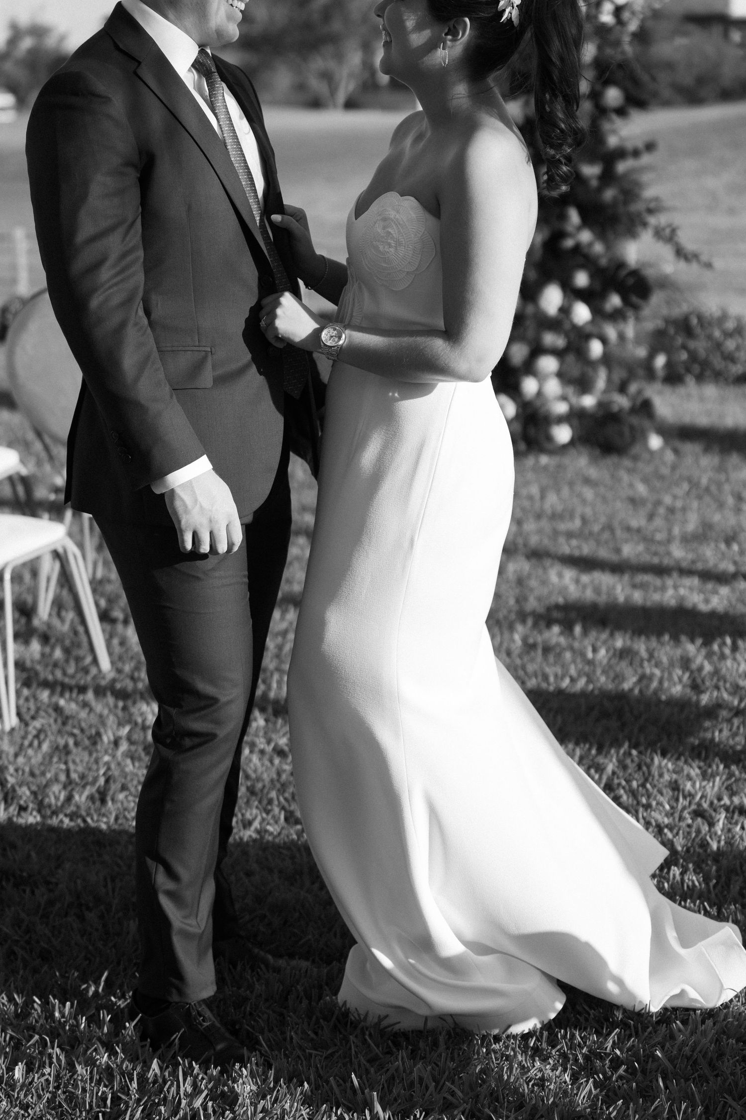 Black and white photo of a couple in formal attire on a grassy lawn.