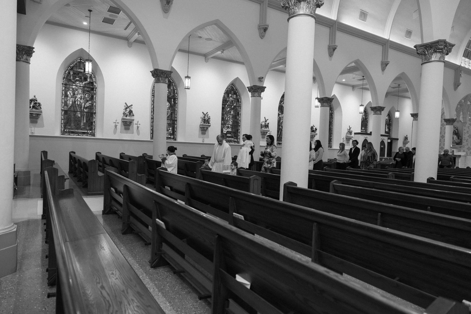 Interior of a historic church with Gothic arches and empty wooden pews in black and white.