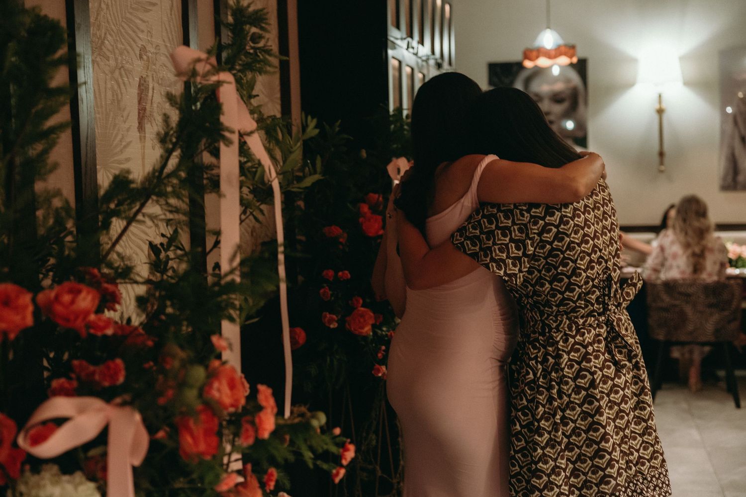 Festive party venue decorated with red floral arrangements and warm lighting.