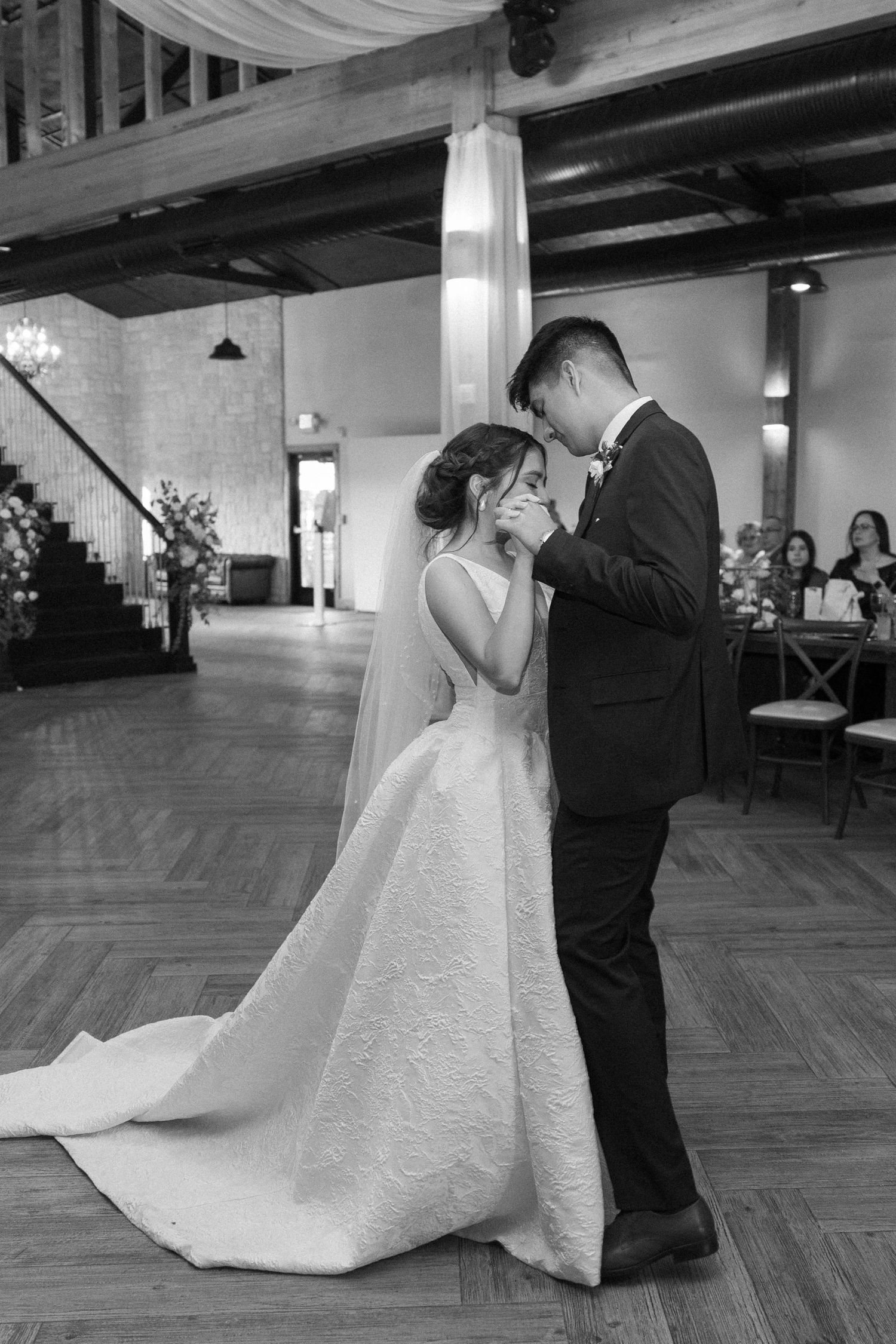 Wedding couple dancing in an elegant ballroom with hardwood floors.