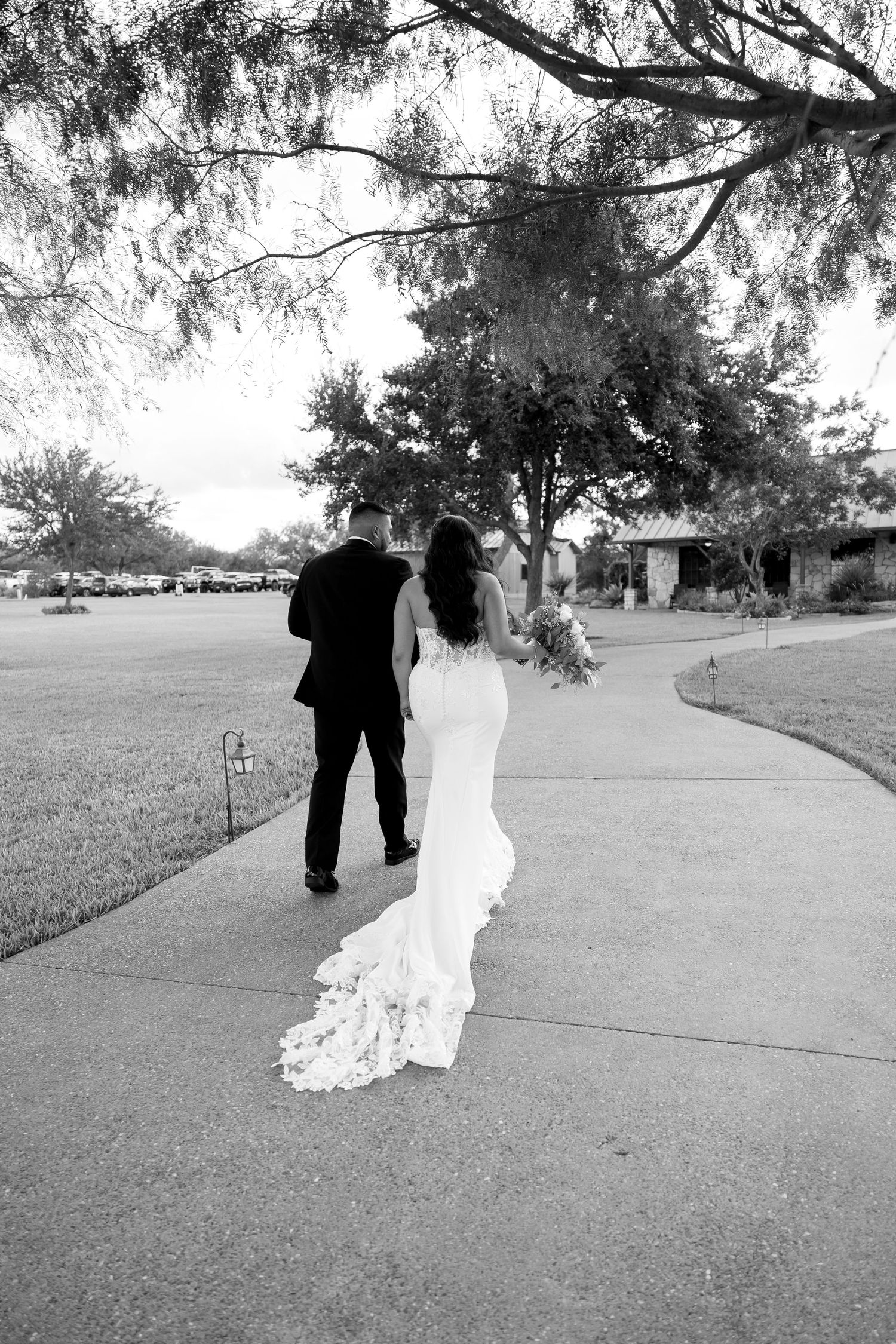 Black and white photo of couple walking along outdoor path after wedding ceremony.