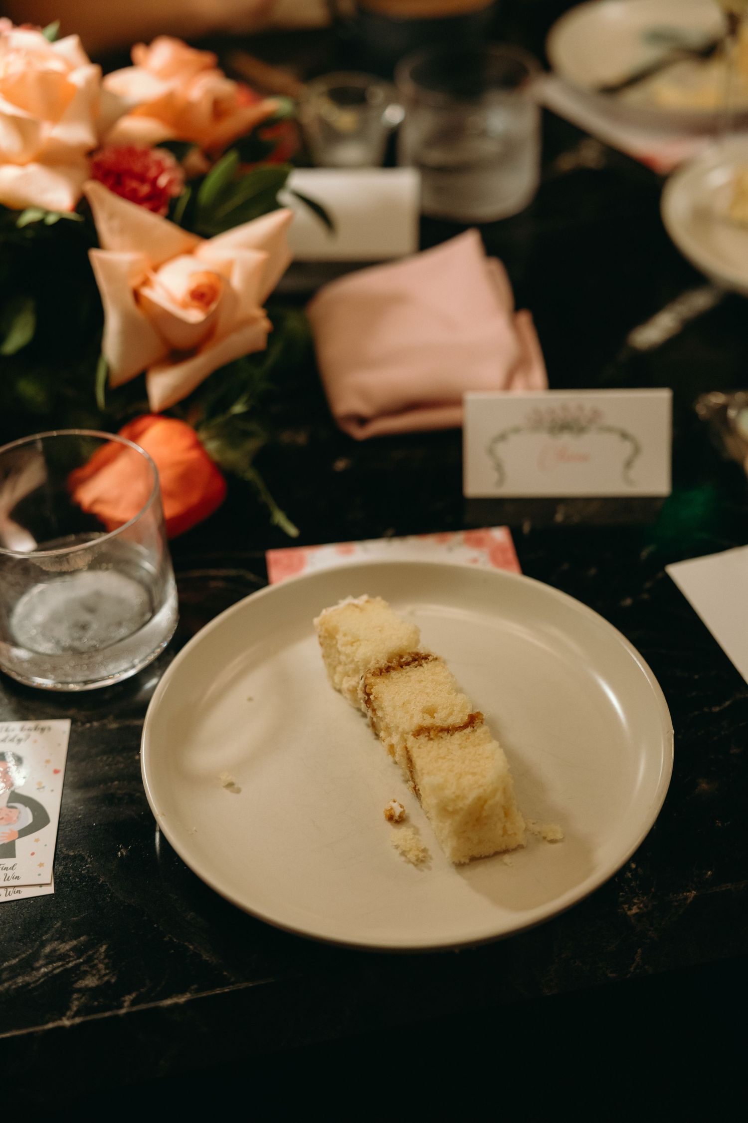 White plates with cake slices and floral decorations on a dark table setting.
