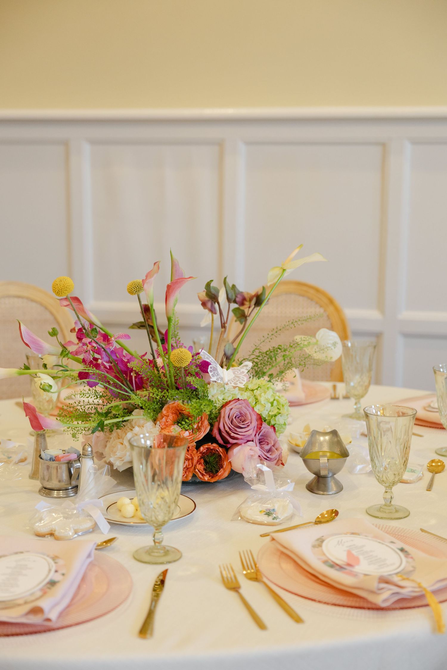Elegant table setting with colorful floral centerpieces and gold cutlery for a romantic celebration.